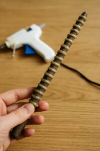 a komplett with Heißkleber verzierter DIY-magic wand wird in the Hand gehalten – perfekt als creative Bastelidee for ae Zauber-scavenger hunt othe aen magischen kids birthday.