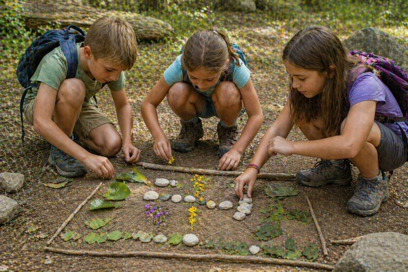 Kids using natural items — leaves, stones, and flowers — to create a secret nature code outdoors